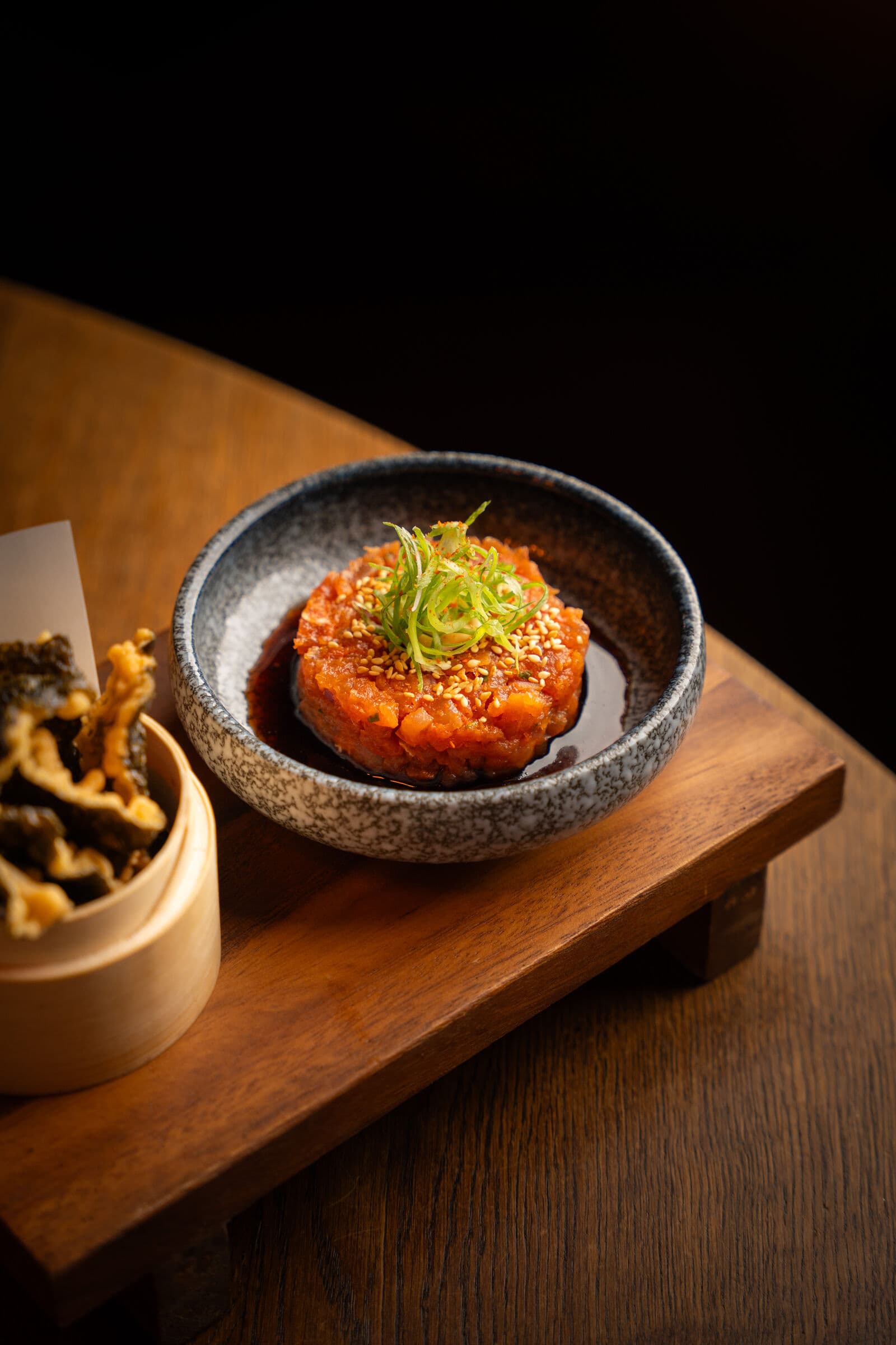 Tonijn tartare in een schaal, geserveerd op een houten plankje